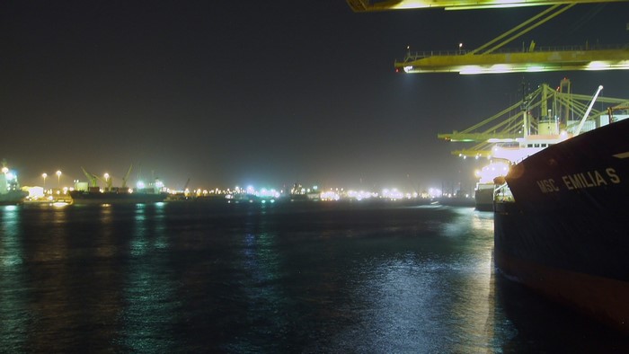 Night view of a busy port with ships and cranes