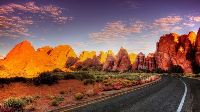 Desert road with rock formations at sunset