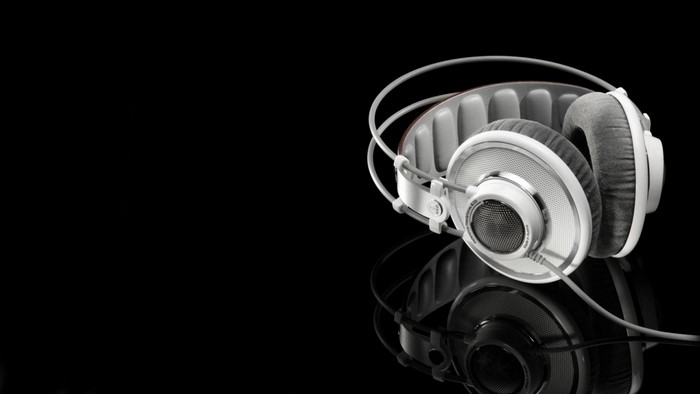 White AKG headphones on a black reflective surface
