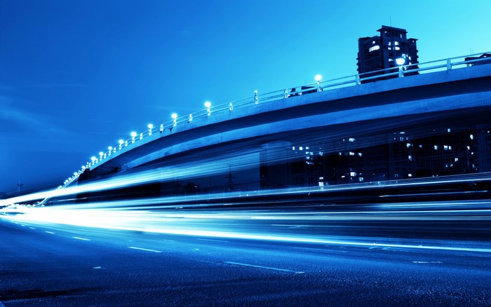 Blue light trails under a bridge at night
