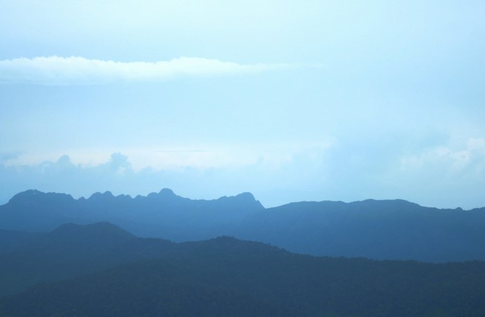Silhouetted mountain ranges under a pale blue sky