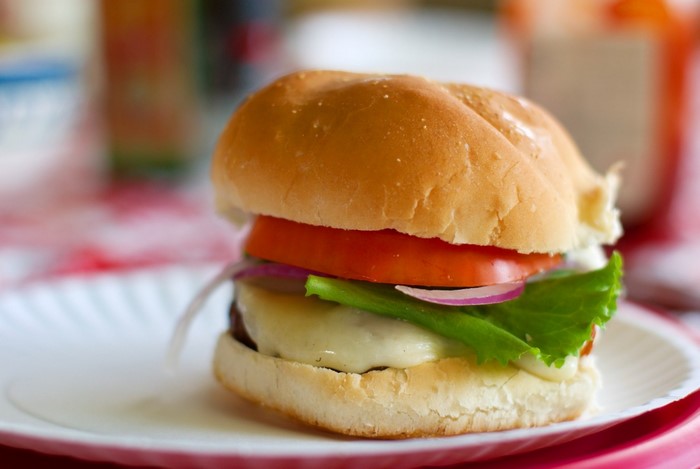 Cheeseburger with tomato, lettuce, and onion on a bun