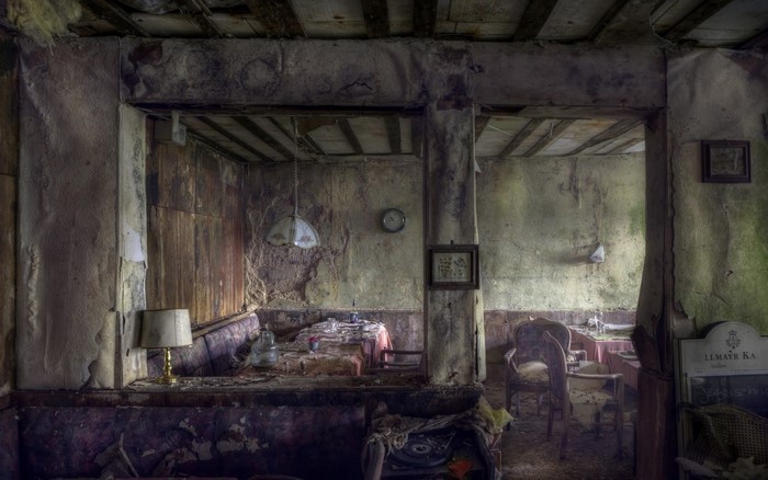 Abandoned restaurant interior with decaying furniture and tables