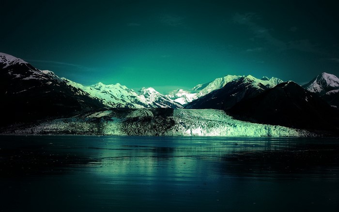 Snow-capped mountains and glacier reflected in dark water