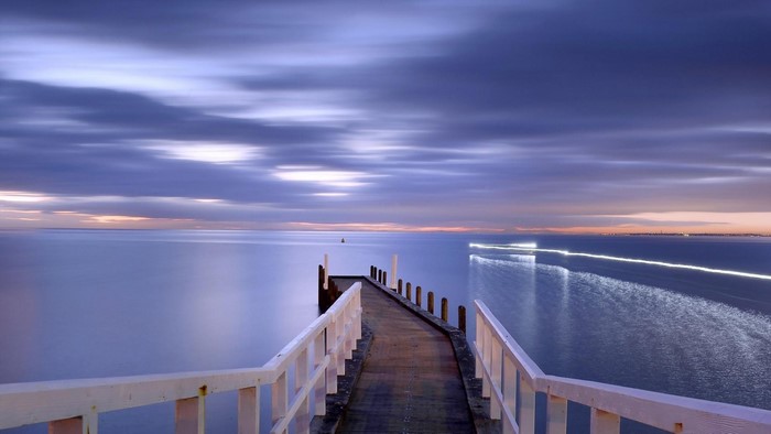 Pier over the sea at sunset with light trails