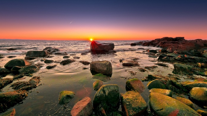 Sunset over a rocky coastline with waves