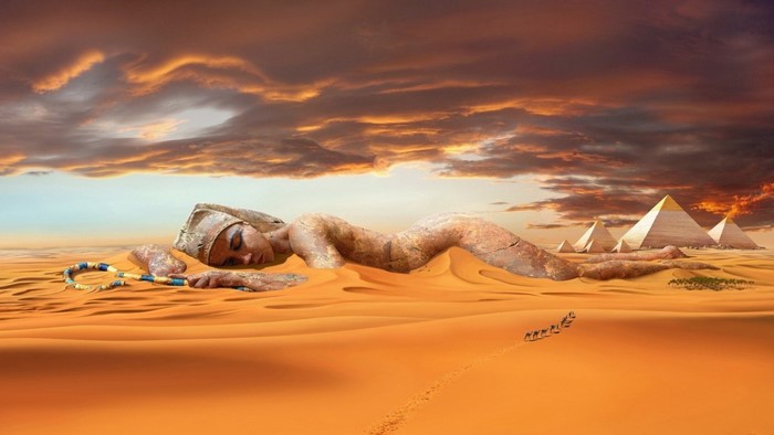 Giant stone woman sleeping in the desert with pyramids