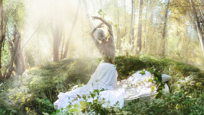 Woman with vines in a sunlit forest