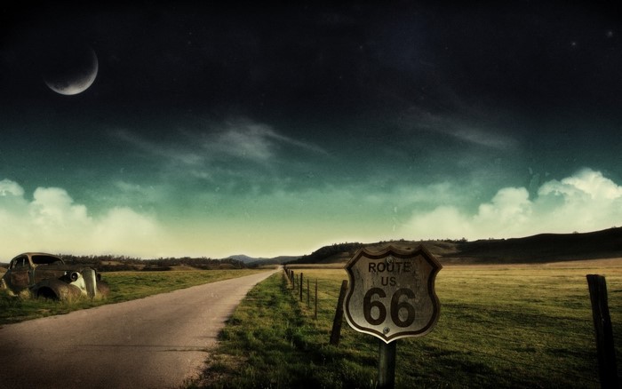 Route 66 sign and abandoned car at night