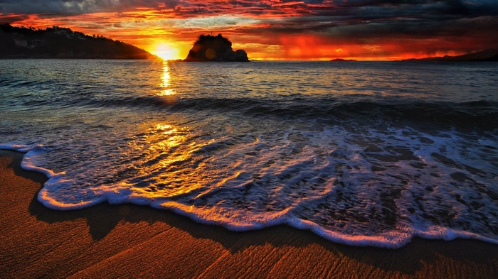 Sunset over the ocean with waves on the beach