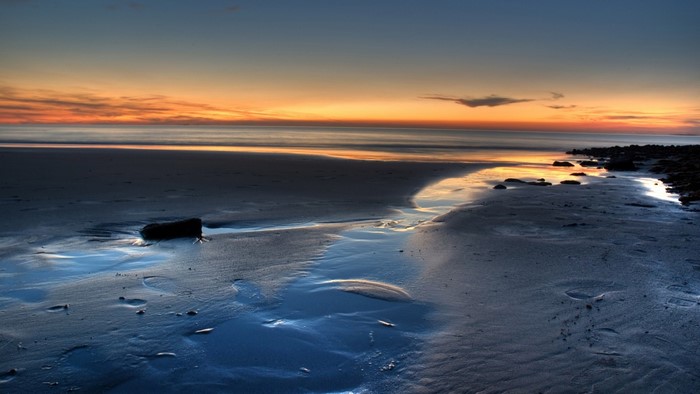 Sunset over the ocean with a sandy shore