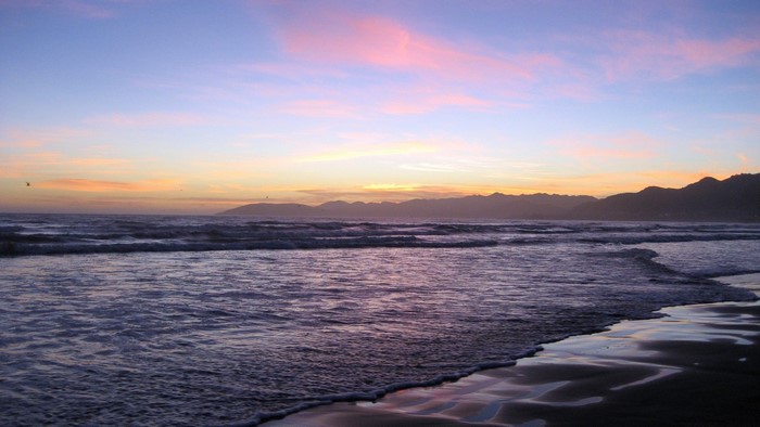 Sunset over the ocean with mountains on the horizon