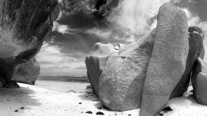 Monochrome beach with large granite boulders and cloudy sky