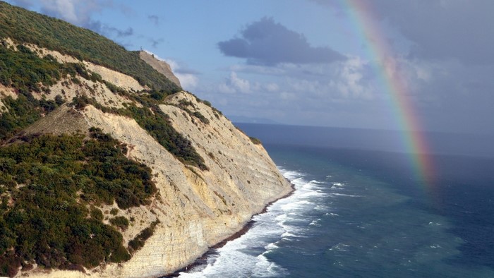 Cliff overlooking the sea with a rainbow