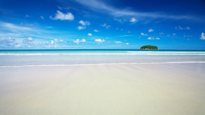 Tropical island beach with blue sky and calm ocean waves