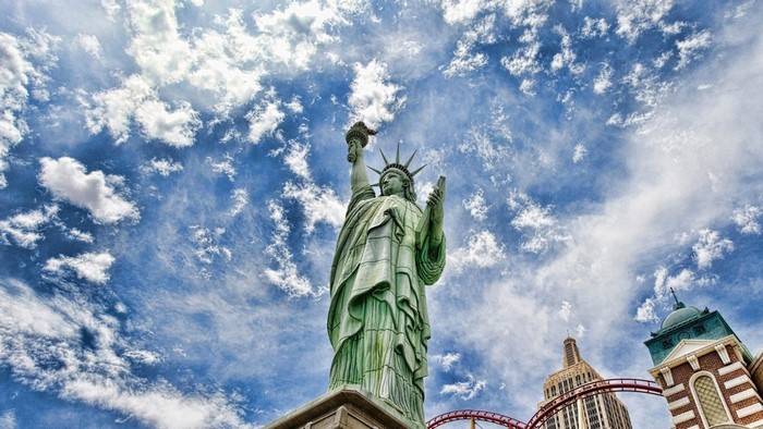 Statue of Liberty replica with roller coaster and skyscrapers