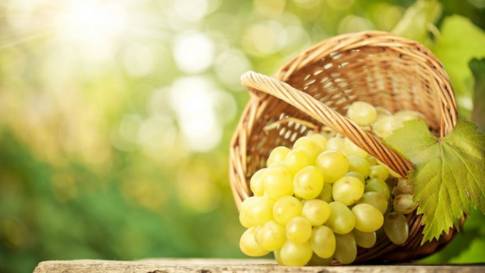 Basket of green grapes with a leaf