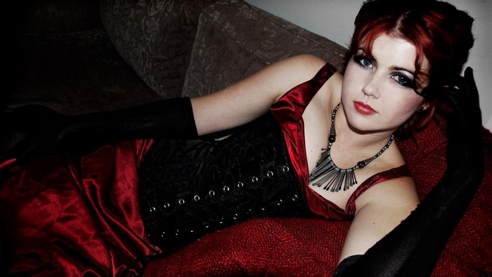 Woman with red hair and blue eyes wearing a corset and dress
