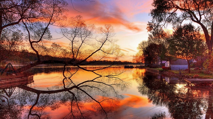 Sunset over a calm lake with trees and reflections