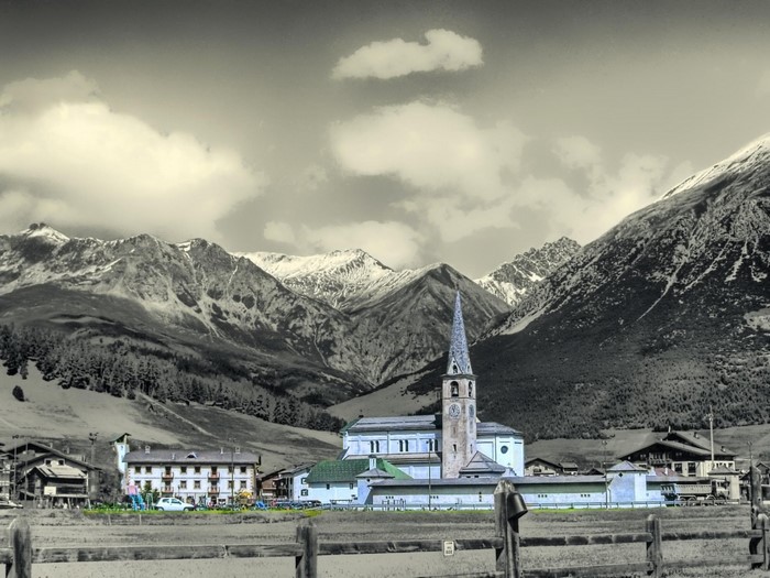 Mountain village with church and snow-capped Alps