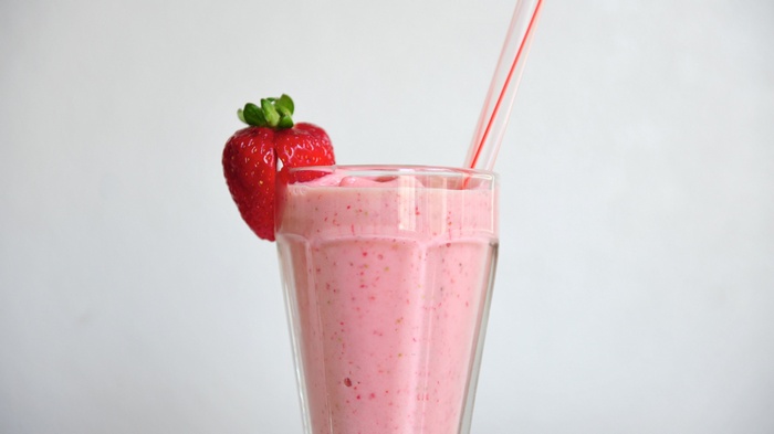Strawberry smoothie in a glass with a straw