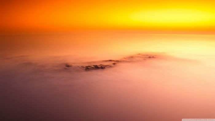 Sunset over the ocean with fog and rocks