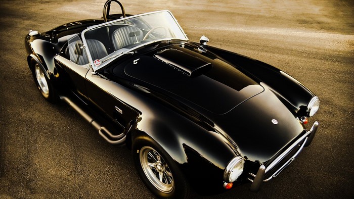 Black Shelby Cobra sports car on asphalt