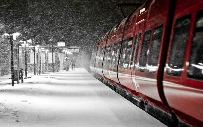 Red train on a snowy platform at night
