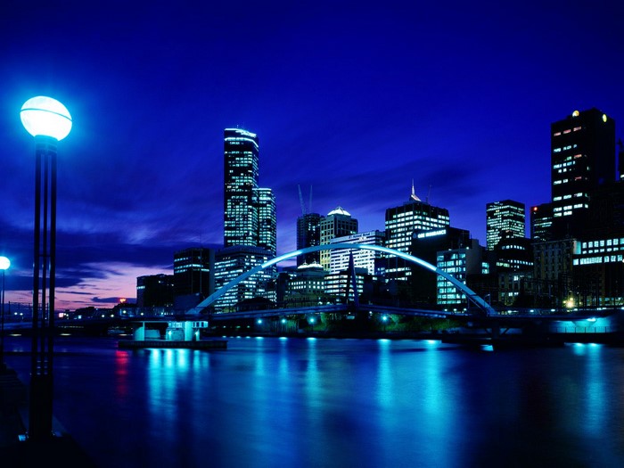City skyline at night with river and bridge