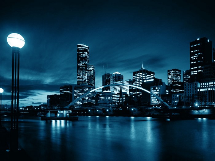 City skyline at night with river and bridge