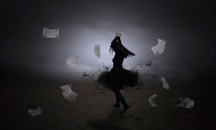 Silhouette of a woman dancing with papers flying