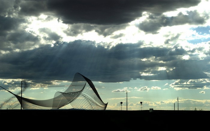 Sculpture against dramatic sky with sunbeams
