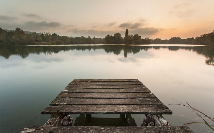 Wooden dock on a calm lake at sunset