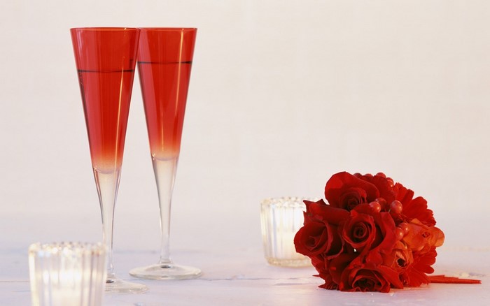 Two red champagne glasses with a bouquet of red roses