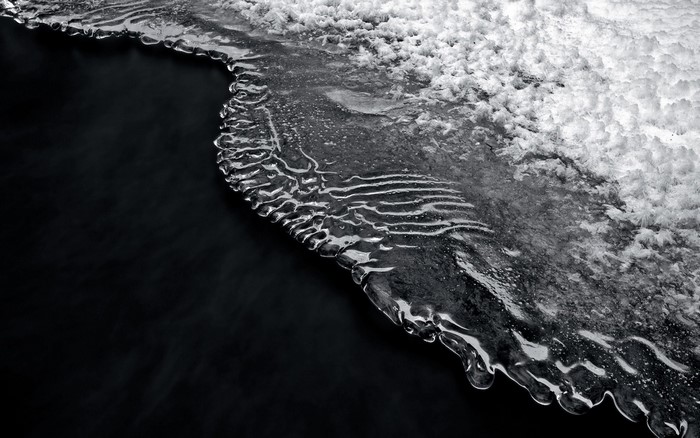 Monochrome close-up of ice formation on dark water