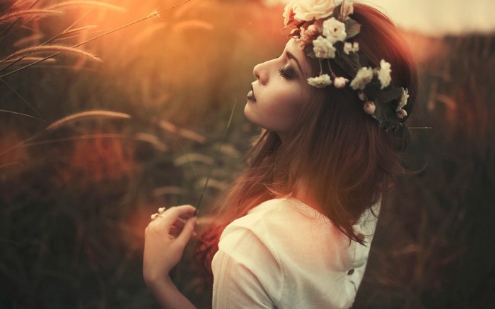 Woman with flower crown in field at sunset