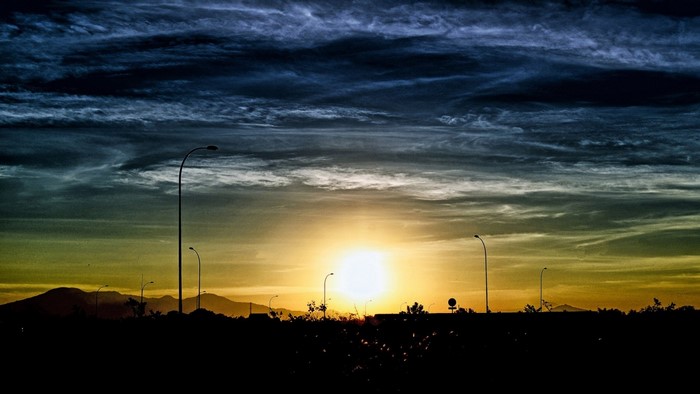 Sunset over a silhouetted landscape with streetlights