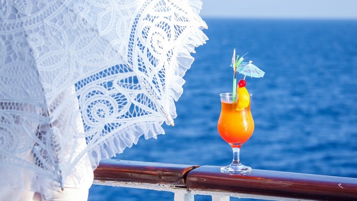 Cocktail on a railing with a white umbrella and the ocean