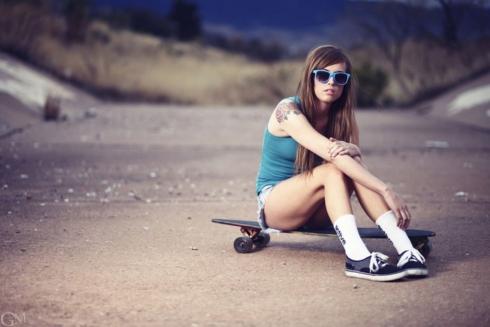 Girl with skateboard wearing blue sunglasses
