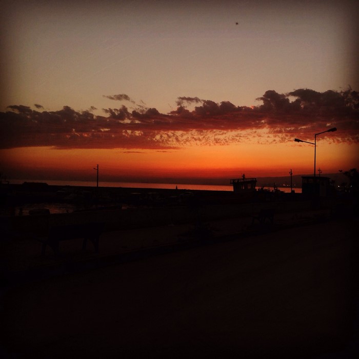 Sunset over the sea with clouds and a street lamp