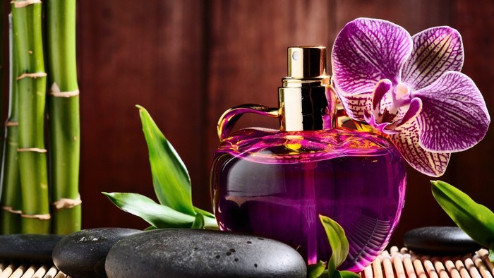 Purple perfume bottle with orchid, bamboo, and stones