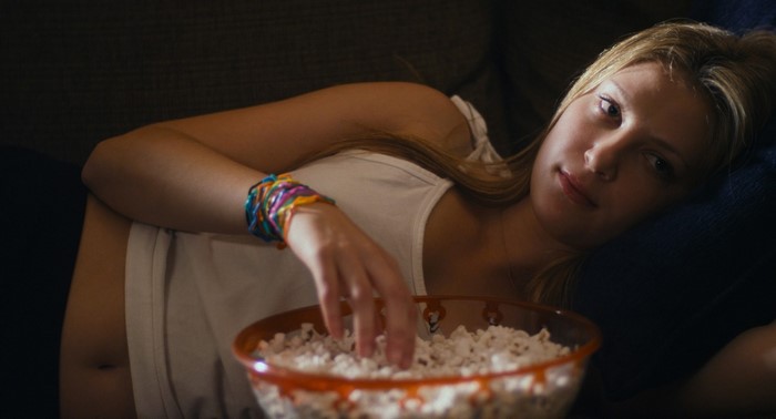 Zoe Levin eating popcorn on a couch