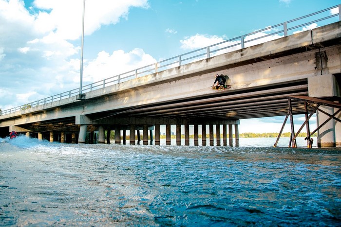 Wakeboarder jumps under a bridge