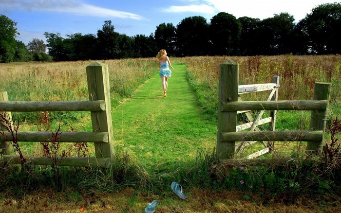 Woman running on a grassy path through a field