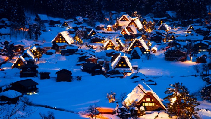 Snowy village at night with illuminated houses