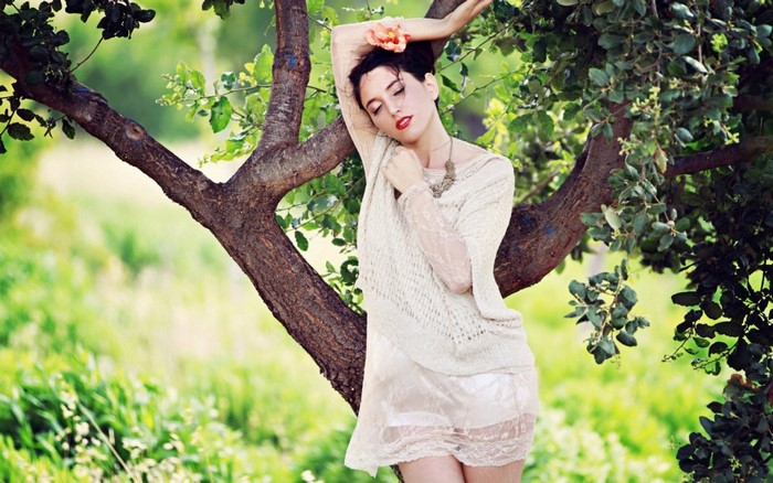 Woman with flower in hair leaning on tree