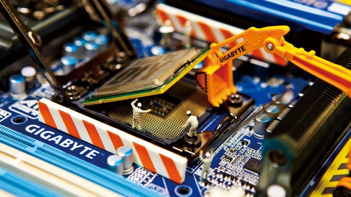 Miniature figures installing a CPU on a Gigabyte motherboard