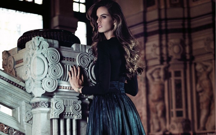 Woman in black dress posing by ornate pillar