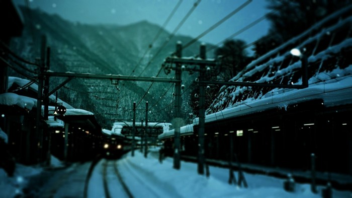 Snowy train station at night with mountains
