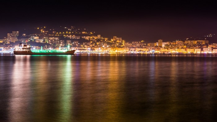 Cityscape at night with ship and reflections